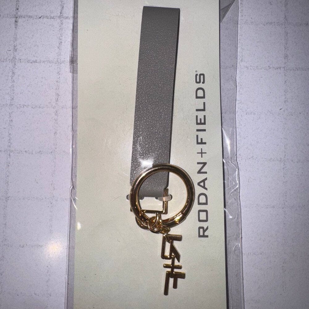 Rodan and Fields gray leatherette & gold metal signature R&F charm key chain